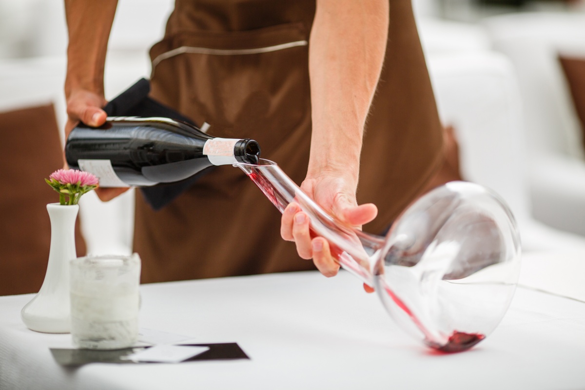 Ein Kellner dekantiert Rotwein in eine große Glaskaraffe, um den Wein zu belüften.